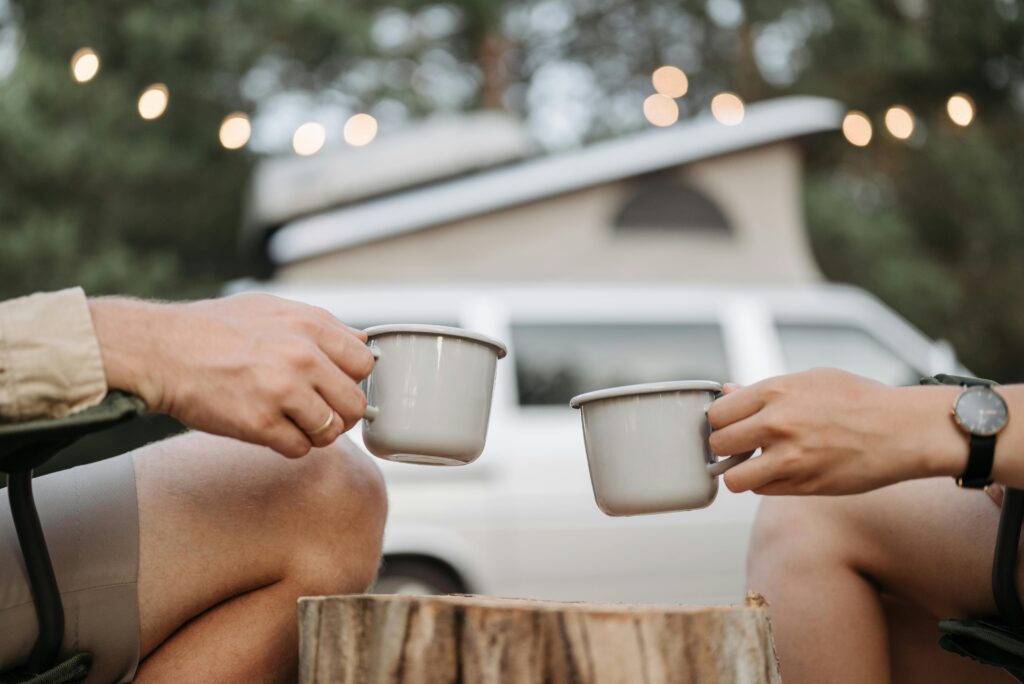 Couple holding two coffee cups at campsite